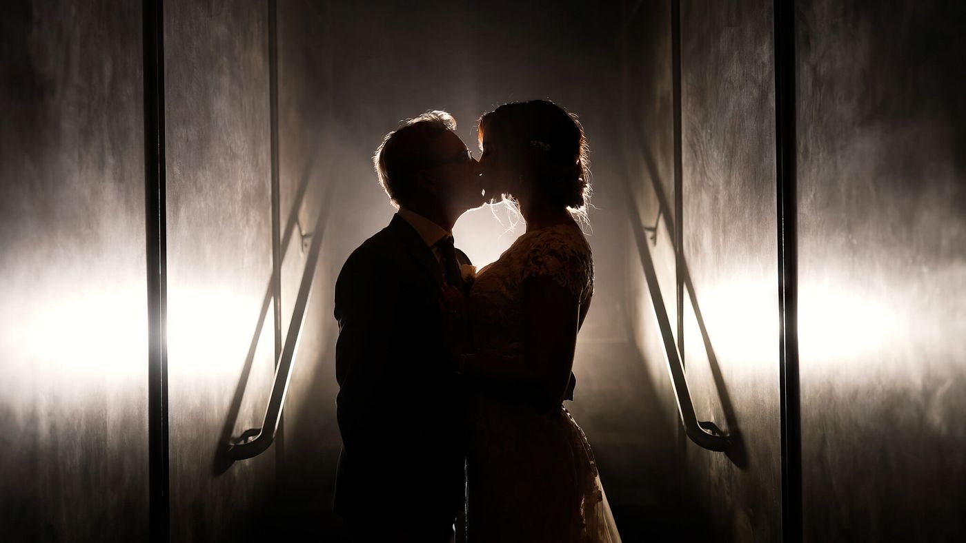Bride and groom silhouetted in a dramatic kiss