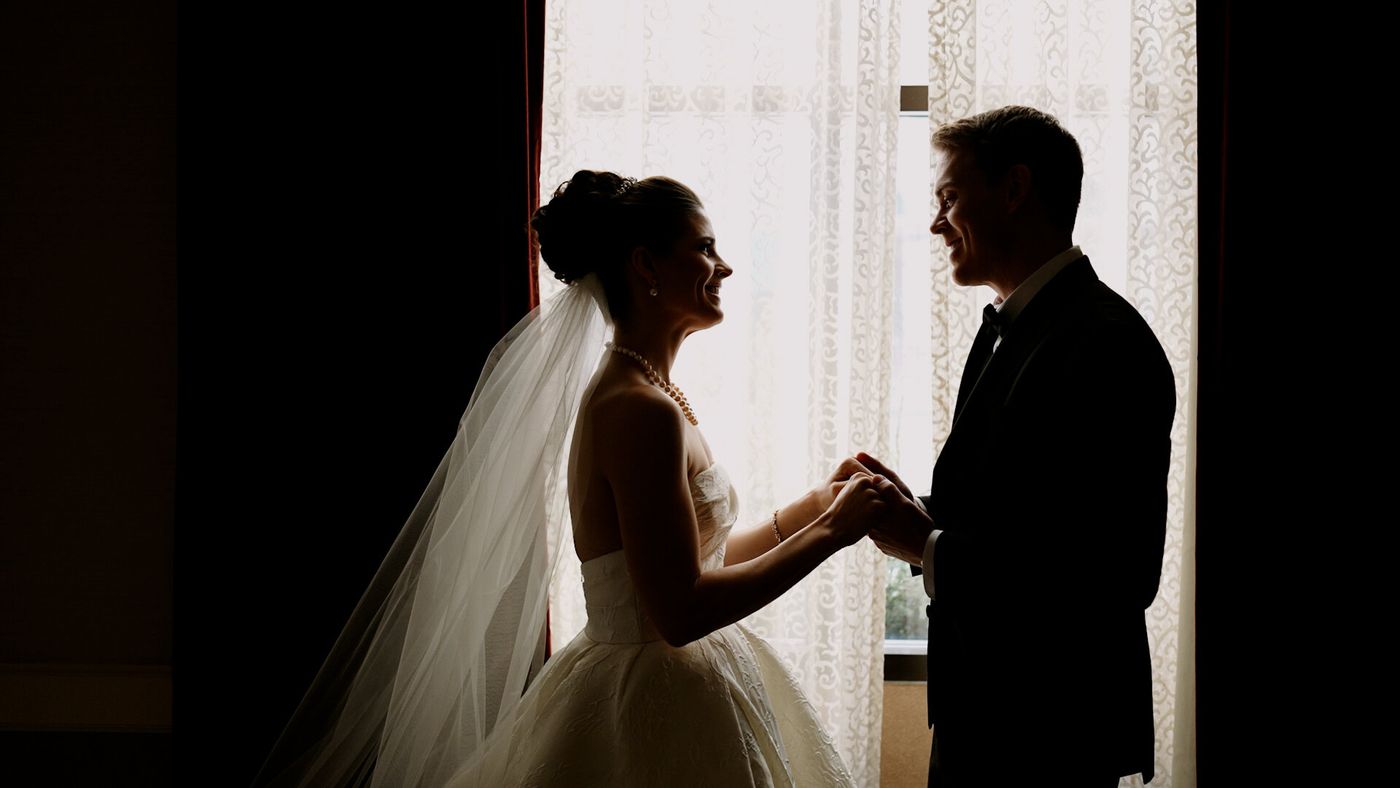 Bride and groom holding hands in soft window light